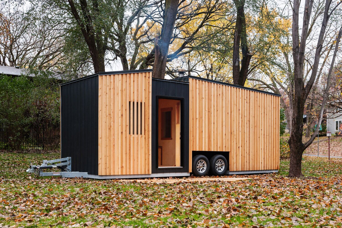 The Surly Sauna exterior, cedar and black metal cladding beneath autumn trees