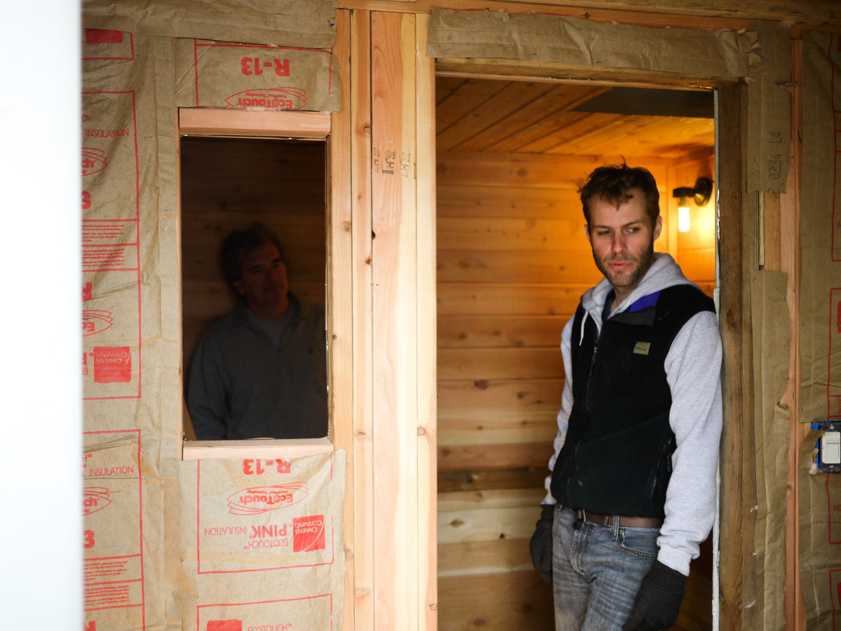 Builder standing beside a sauna doorway